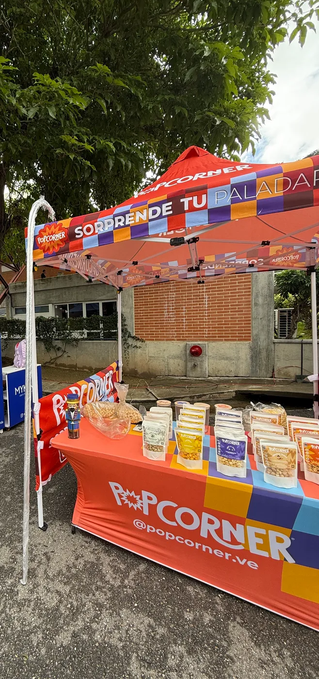 Carpa Popcorner naranja con mesa de activación y producto en celofán
