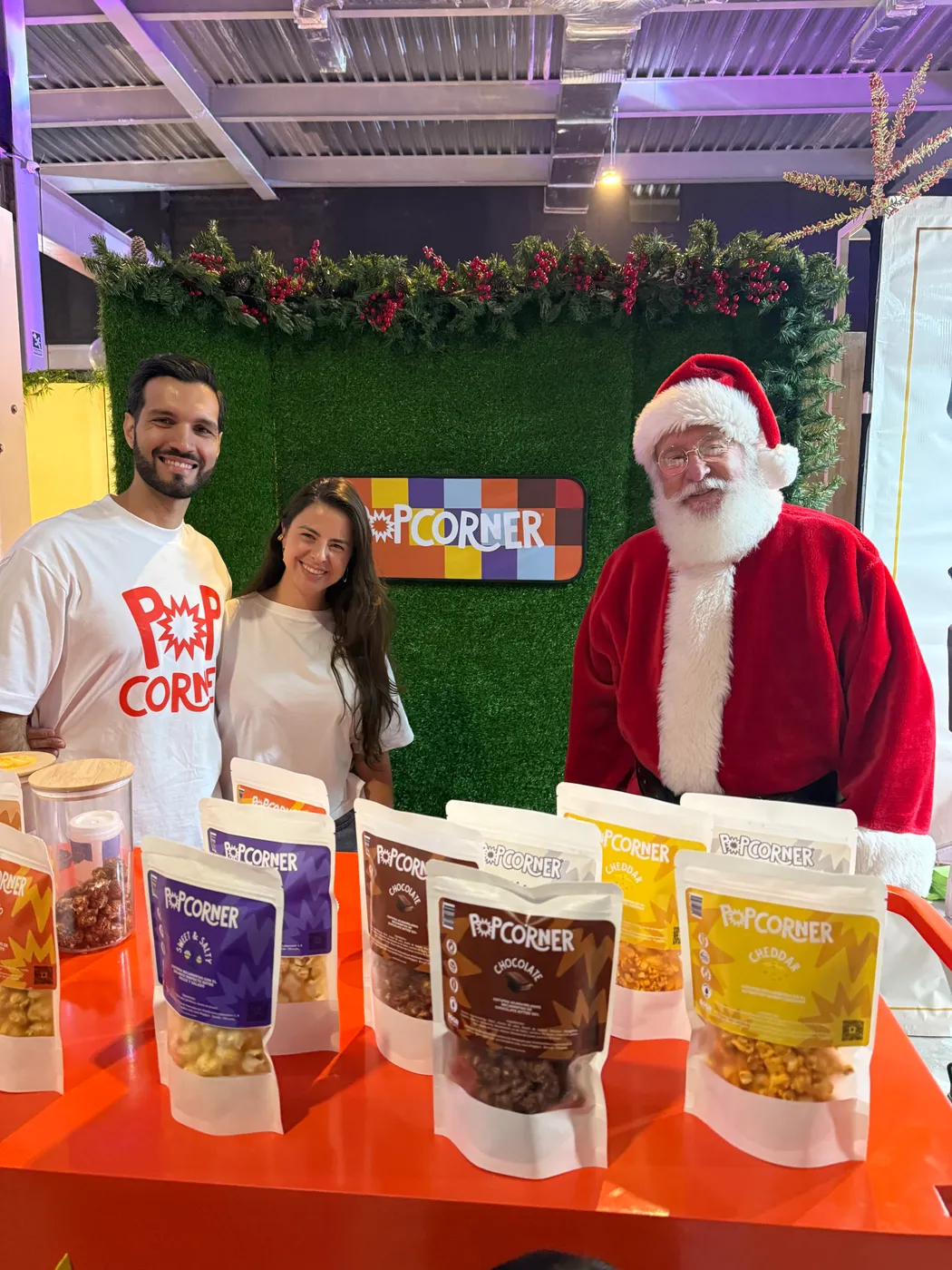 Bar de cotufas Popcorner con backdrop verde, equipo y Santa Claus en evento navideño